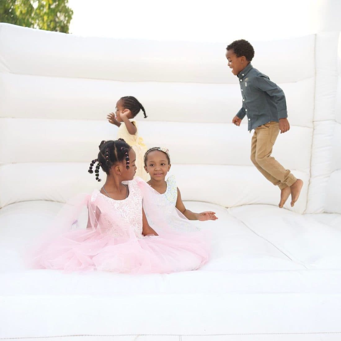 Children playing on a white bouncing castle at a birthday celebration