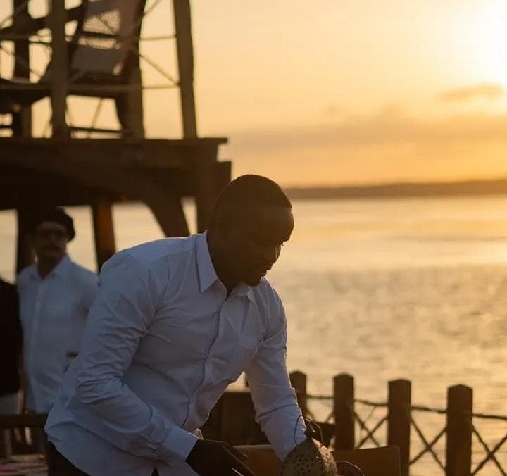 Screbick setting a table at a beach dinner as the sun sets over the water