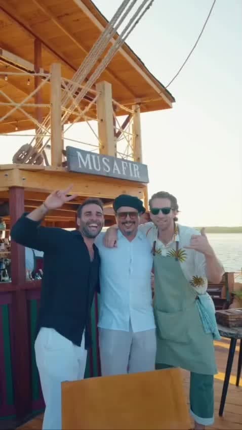 Screbick with two delighted guests at a coast-side sunset dinner