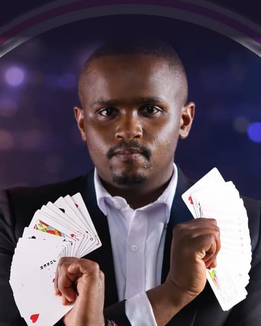 Screbick the Magician in a black suit, a fan of playing cards in each hand